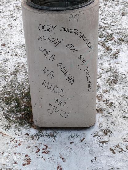 Betonowy śmietniczek o podstawie w kształcie zaokrąglonego kwadratu, a szczycie okrągłym, z metalowym wkładem. Na popielatej powierzchni pisakiem napisano:

"""
Poet

Oczy zwierciadłem
suszy gdy się puszysz
cała głucha
na
kurz....
no
już!
"""

Dłuższe wersy napisano po łuku, z lewej w dół.